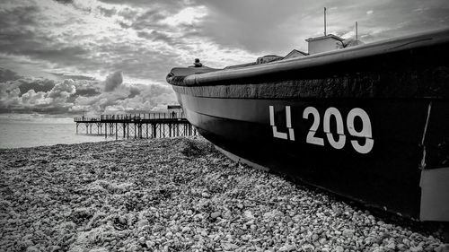 Boat moored on pier by sea against sky