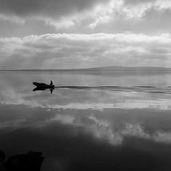 Boats in sea against cloudy sky