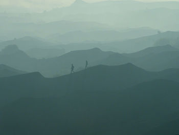 Scenic view of silhouette mountains during foggy weather