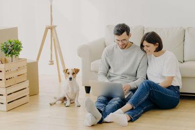 Smiling couple using laptop while sitting at home