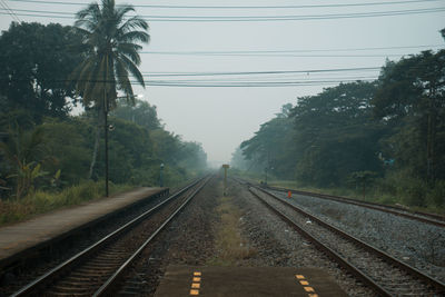 Railroad tracks by trees against sky