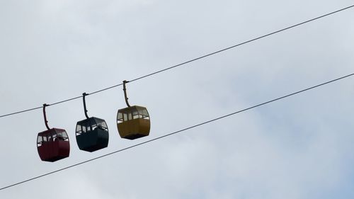 Low angle view of overhead cable cars against sky
