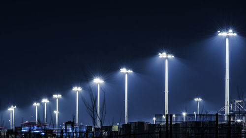 Low angle view of illuminated floodlights against sky at night