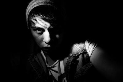 Portrait of young man against black background