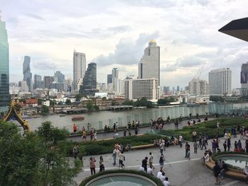 People on modern buildings in city against sky