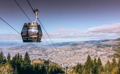 Overhead cable car over mountains against sky