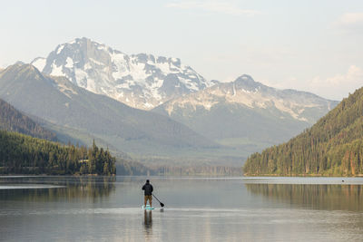 Man on snowcapped mountains by lake against sky