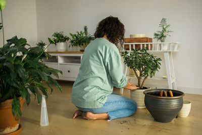 Rear view of woman sitting on table at home