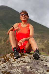 Full length of young woman sitting on rock