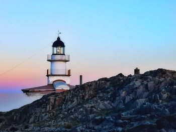 Lighthouse by sea against sky during sunset
