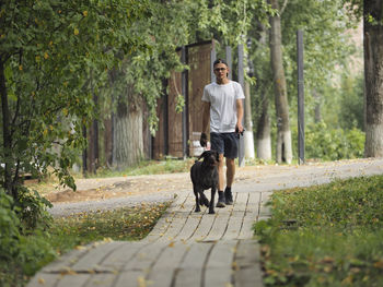 A young man of european appearance walks his dog in the park in the summer. high quality photo