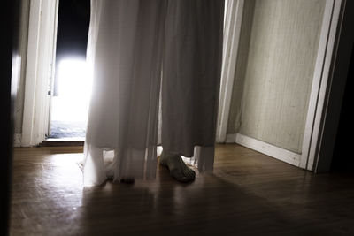 Low section of ghost standing at doorway in cabin