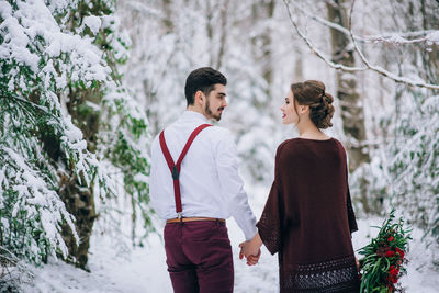 Friends standing on snow covered plants