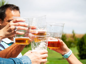 Cropped hands of people drinking beer in glass