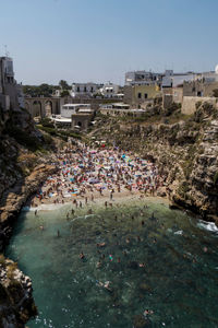 High angle view of people at beach by buildings against clear sky