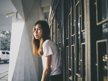 Portrait of young woman standing against wall