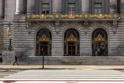 Man walking with dog against san francisco city hall