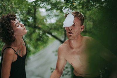 Portrait of shirtless man standing by plants