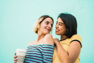 Side view of smiling lesbian couple standing against wall