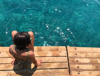 Rear view of woman sitting in swimming pool