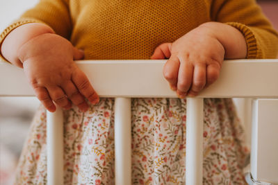 Midsection of baby girl standing in crib at home