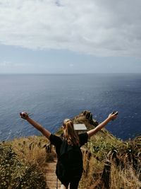 Rear view of woman walking on stairs by sea against sky