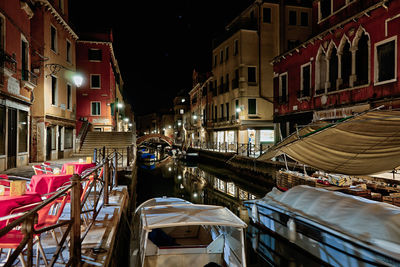 Canal amidst buildings in city at night