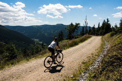 Full length of woman riding bicycle on road against sky