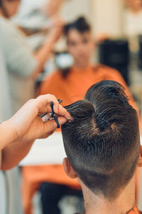 Cropped hands of woman cutting man hair in salon