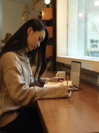 Side view of woman using laptop on table