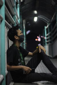 Side view of young man looking at camera