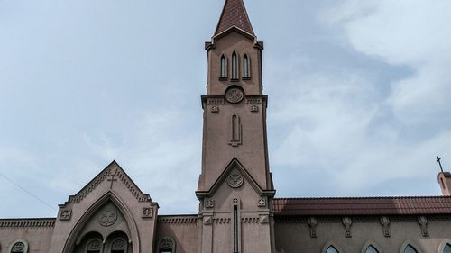 Low angle view of clock tower amidst buildings against sky