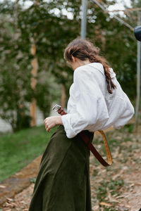 Side view of woman standing against trees