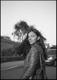 Portrait of smiling young woman standing against sky