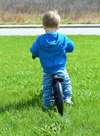 Rear view of boy with bicycle on grass