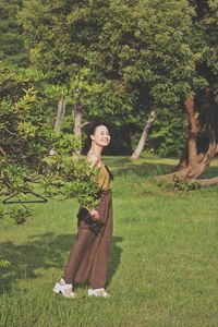 Portrait of smiling young woman on field against trees