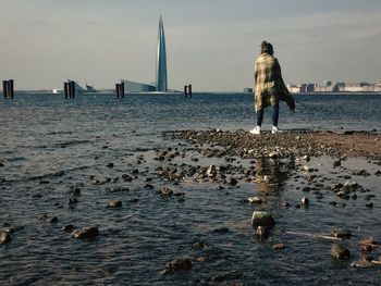 Rear view of woman standing at shore