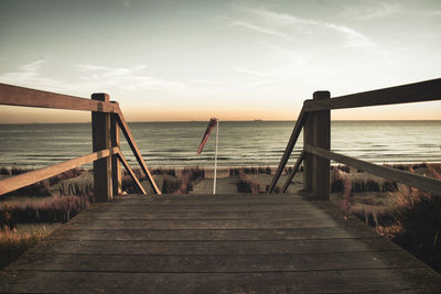 Wooden jetty on pier at beach against sky