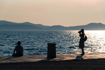 People looking at sea against sky