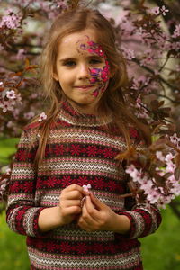 Spring portrait of a six year old girl standing under the blooming pink cherry tree