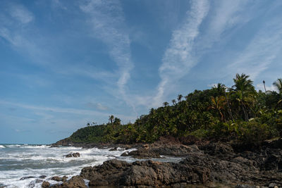 Scenic view of rocks by sea against sky