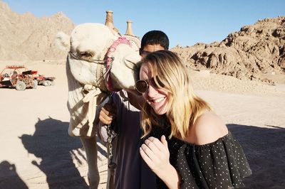 Happy woman with camel at desert