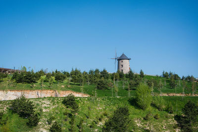 Built structure on field against clear blue sky