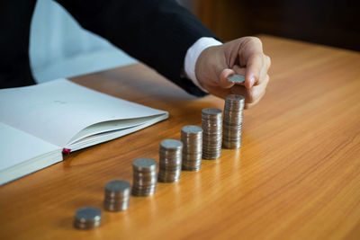 Close-up of hand holding coin on wooden table