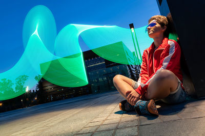 Portrait of young woman sitting outdoor on a ground with abstract pattern made by freeze light