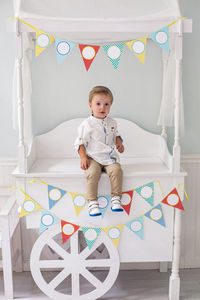 Child sitting on a wooden white cart in the studio as a birthday decoration