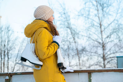 Portrait of young woman with ice skates looking to rink