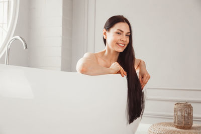 Portrait of smiling young woman sitting in bathroom