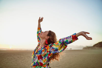 Midsection of woman at beach against sky