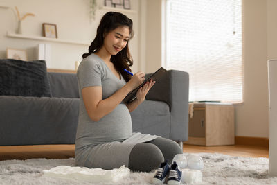 Young woman using phone while sitting on sofa at home